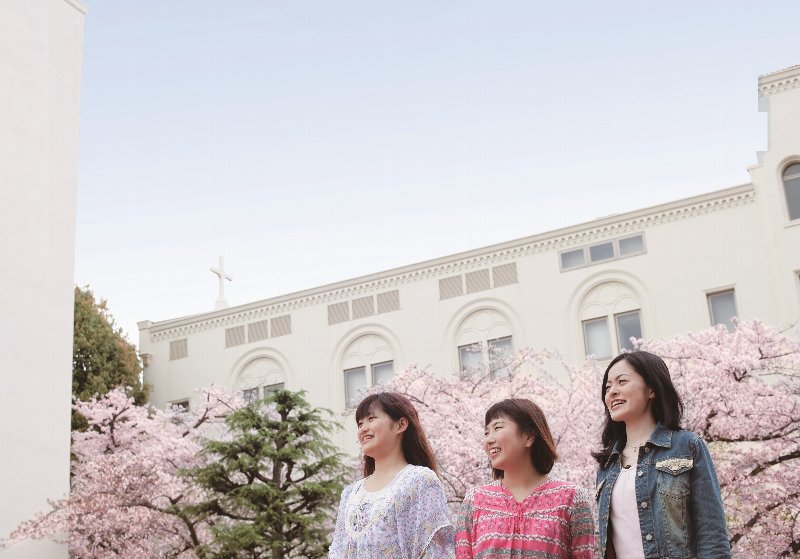 学生の笑顔と桜と学舎・・・春には大学内の桜の花が咲き誇ります。